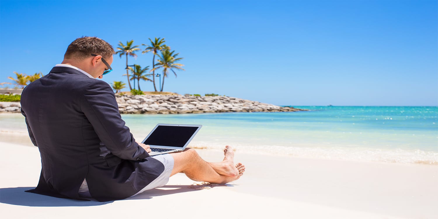 Passive real estate investor sitting on the beach looking at computer - active vs. passive investment concept